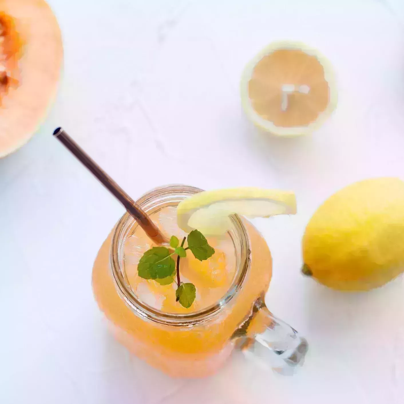 a still life of cantaloupe and lemon mock tail on a white table