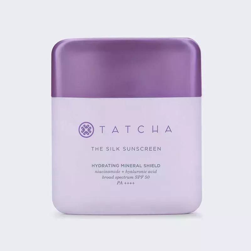 A lavender square bottle of the Tatcha The Silk Sunscreen on a grey background