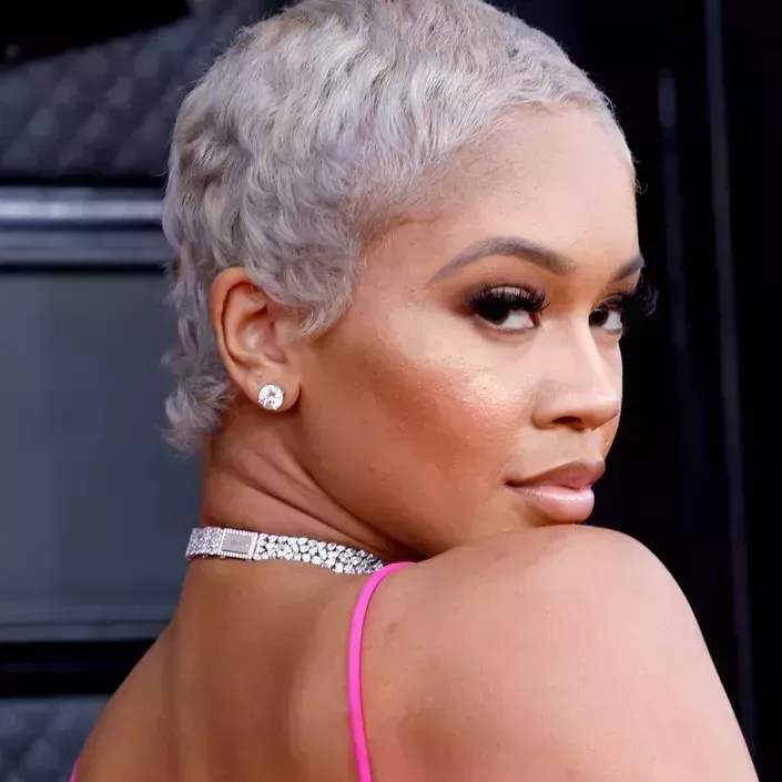 headshot of saweetie with silvery blonde buzzcut and neutral glam makeup 