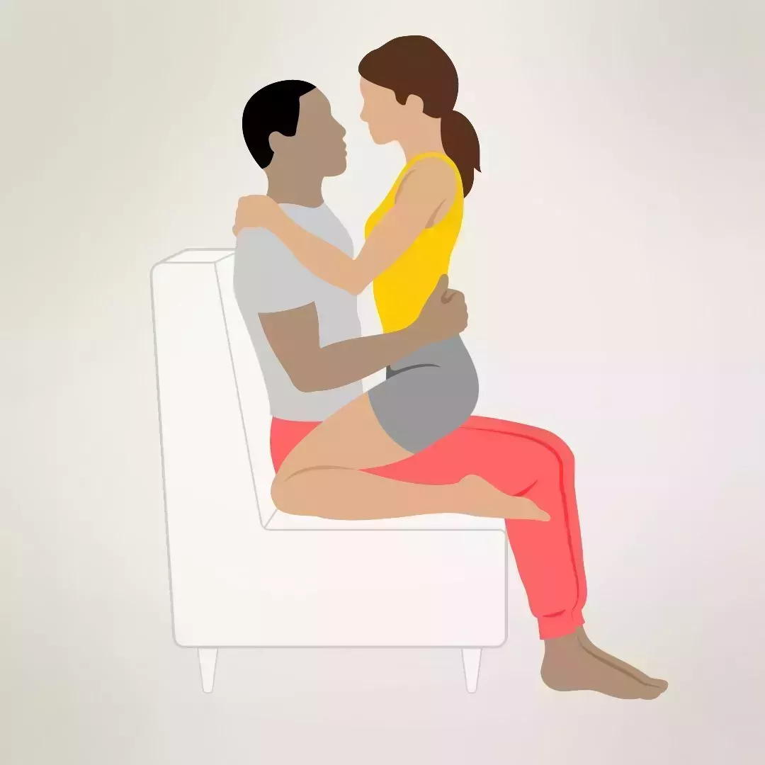 one person straddles another as the couple faces each other in an intimate embrace on a loveseat