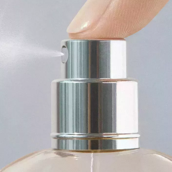 close up image of fragrance bottle with spritz coming out