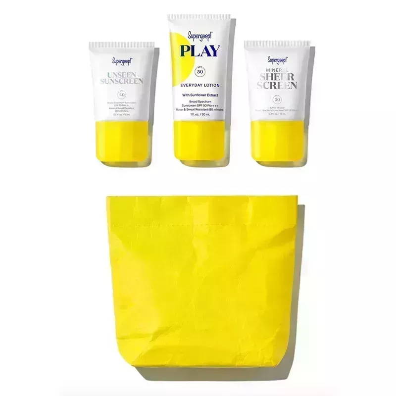 The Supergoop Everyday Superstars SPF Discovery Kit, including mini-size tubes of Unseen Sunscreen SPF 40, PLAY Everyday Lotion SPF 50 with Sunflower Extract, and Mineral Sheerscreen SPF 30 with yellow travel pouch on a white background