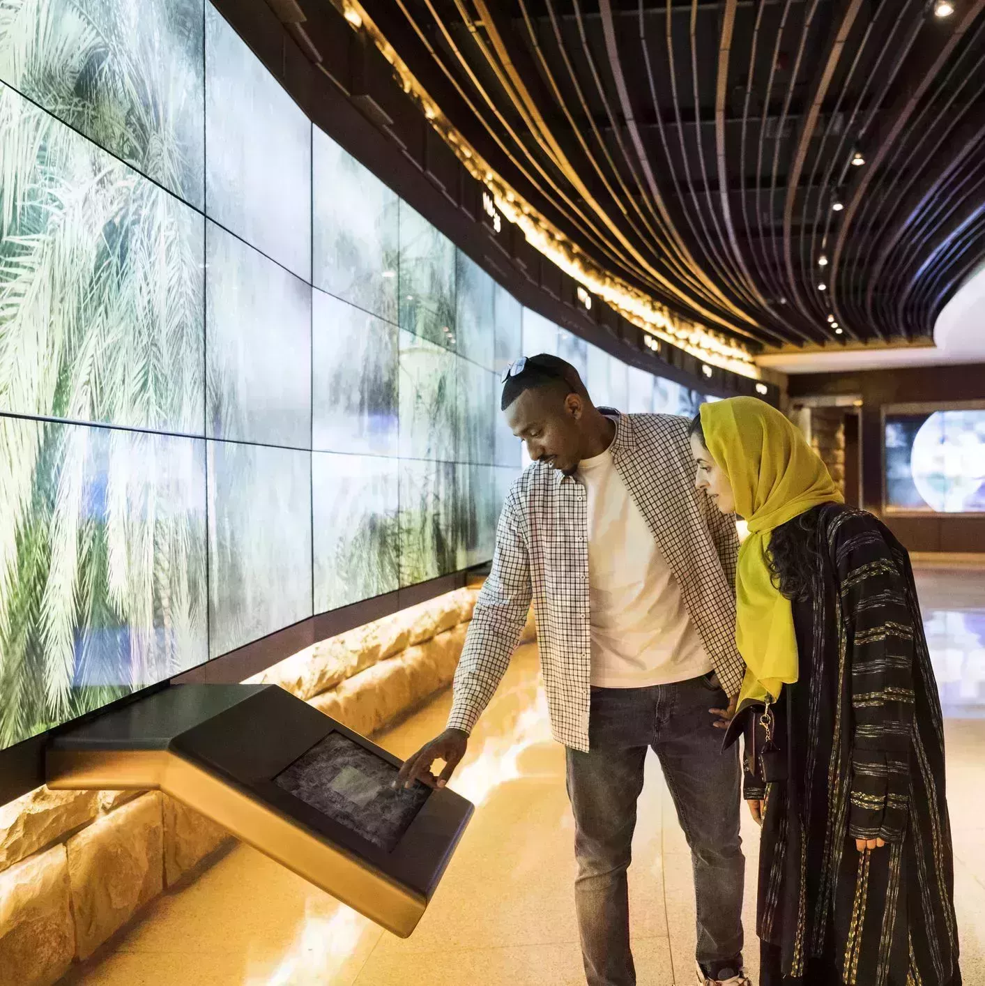 black man and hijabi woman at a museum using a touchscreen