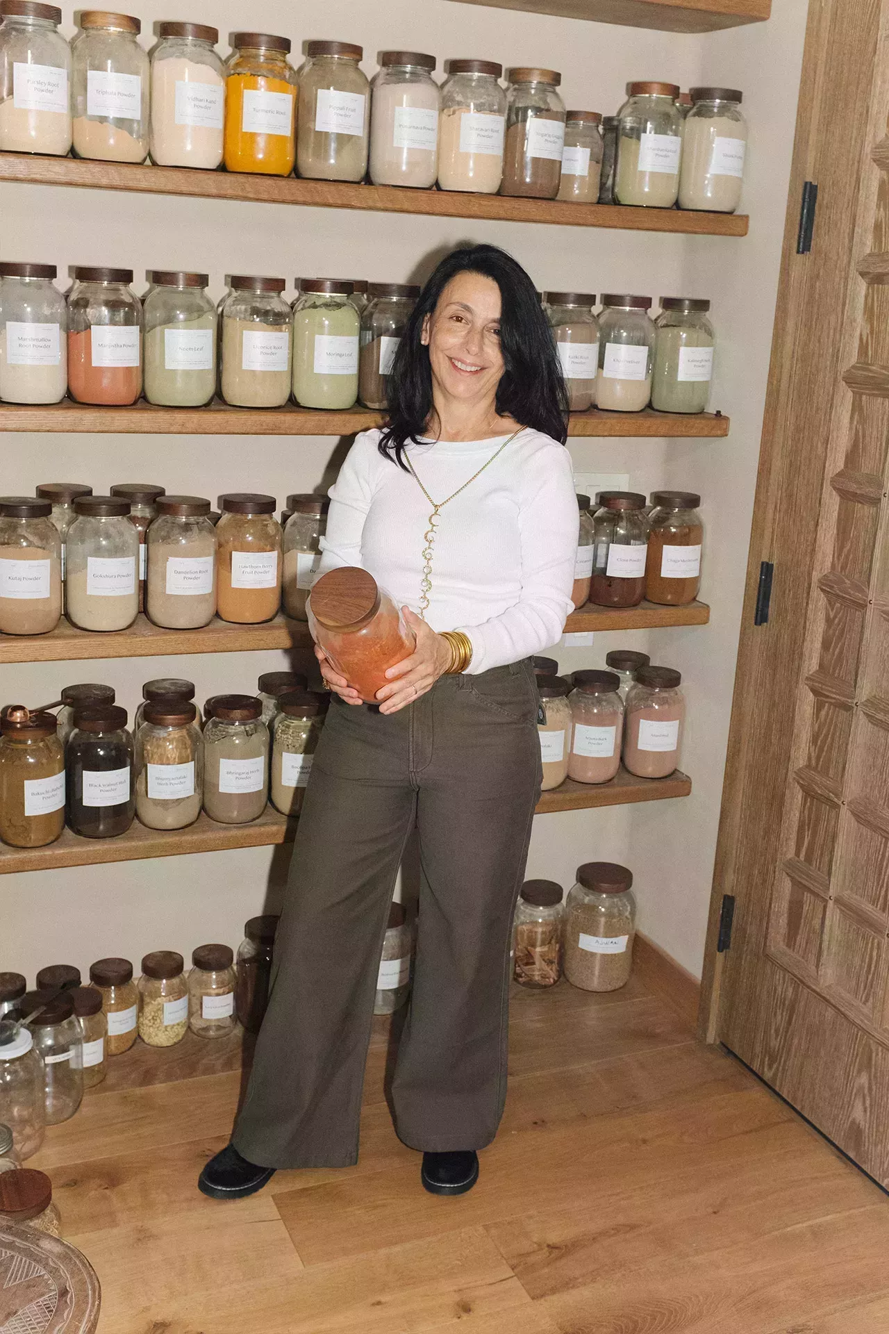 photo of lady holding a jar of a spice behind a wall of spices