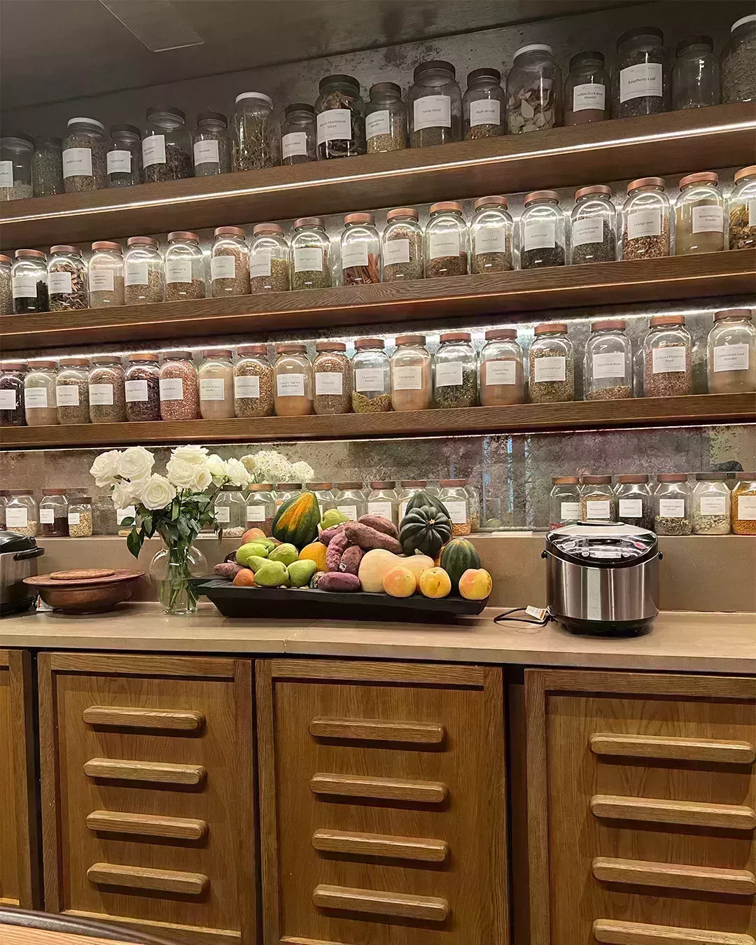 kitchen with a bunch of spices and big bowl of fruit in the center