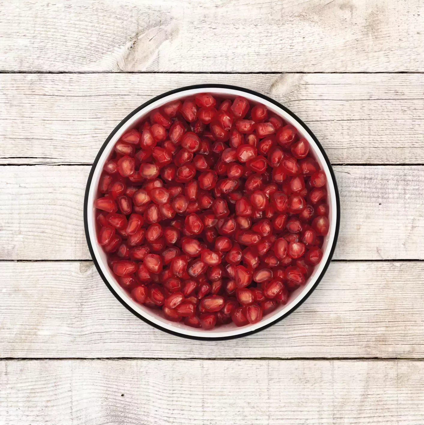 pomegranate seeds bowl on wood background from directly above