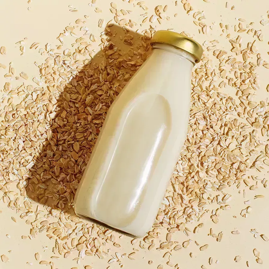 a bottle of oatmilk on top of scattered oats