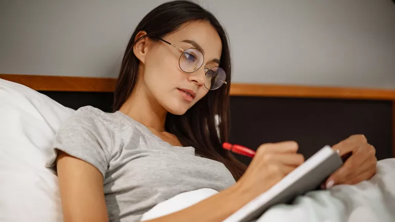 Mujer escribiendo en la cama