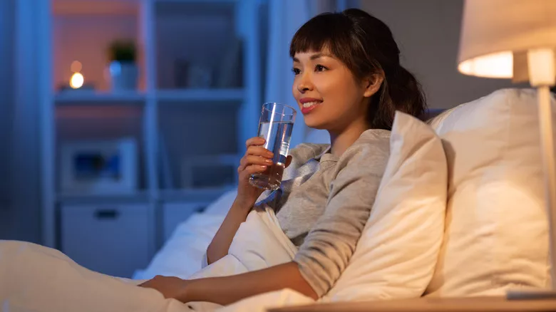 Mujer bebiendo agua en la cama