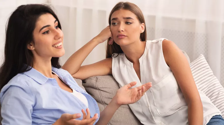 Mujer envidiosa escuchando hablar a una amiga